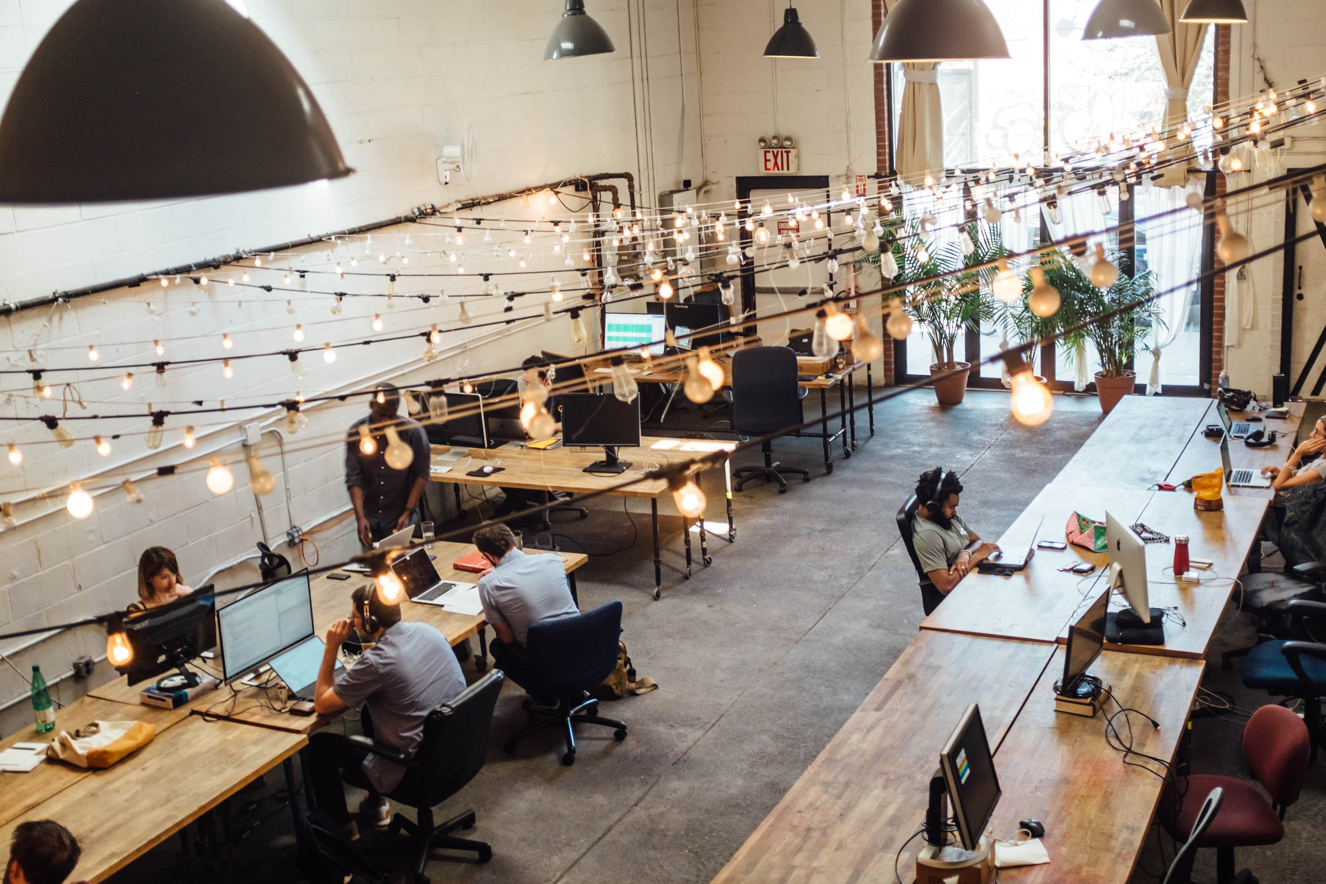 People working in a room with lights hanging on ceiling