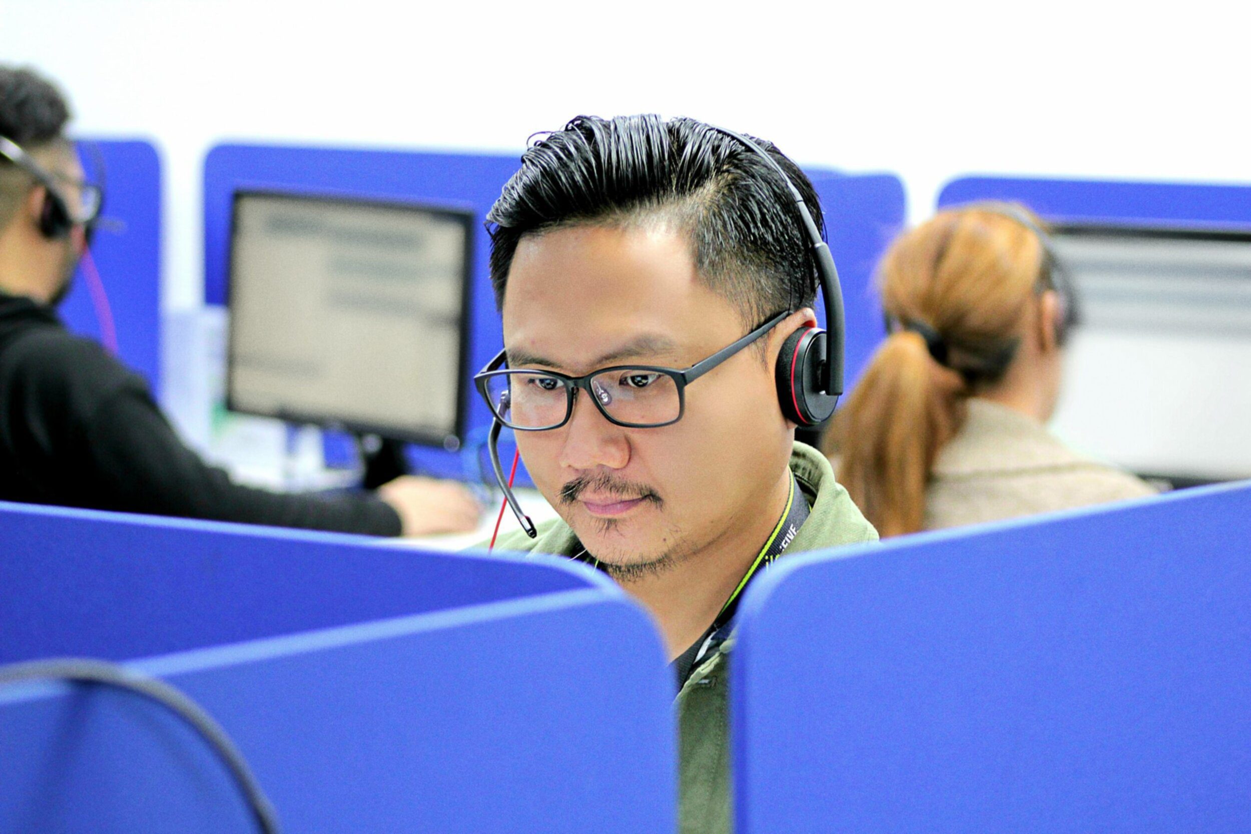 Man with glasses and headset looking at computer screen