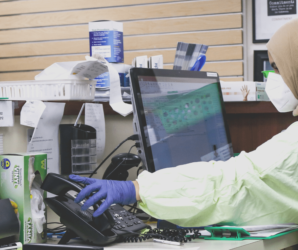 Image of female healthcare profession in full PPC within a hospital referring to a screen