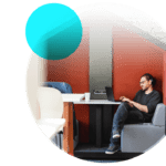 Person sat at laptop with headphones on smiling at screen