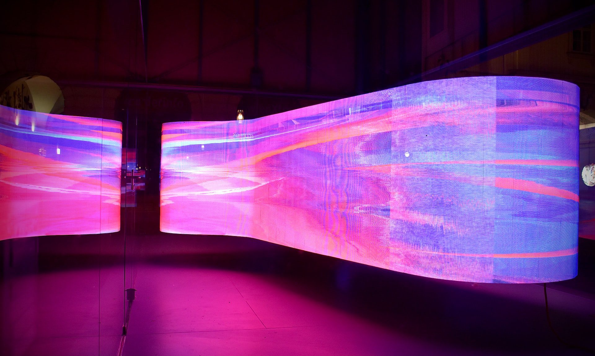 Purple, pink and blue LED design exhibit in darkened room. 
