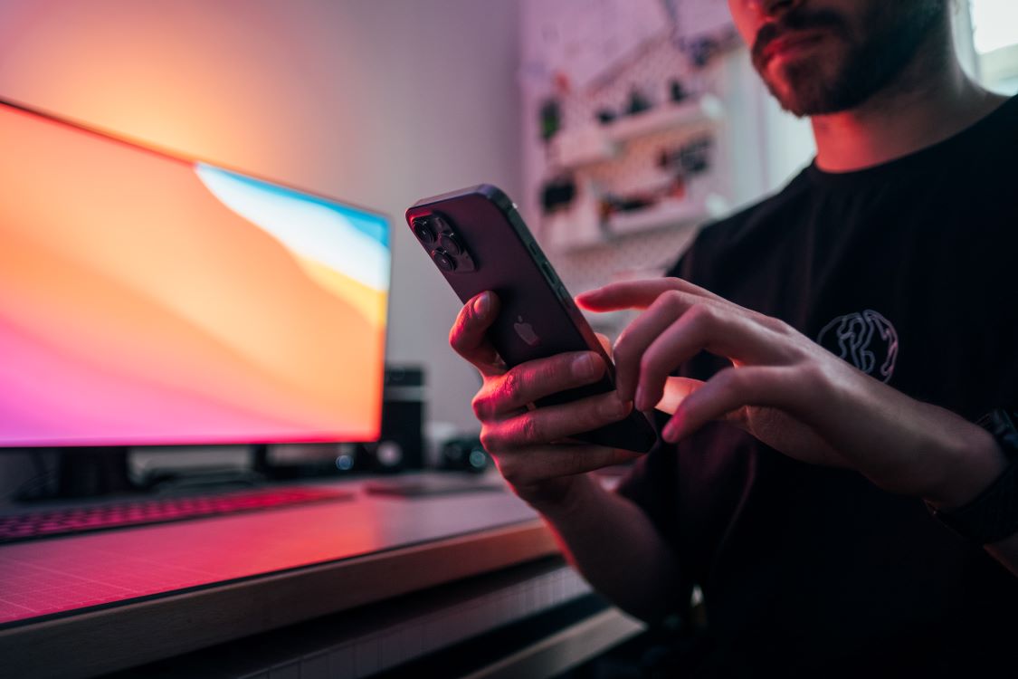 Man using his phone next to the computer