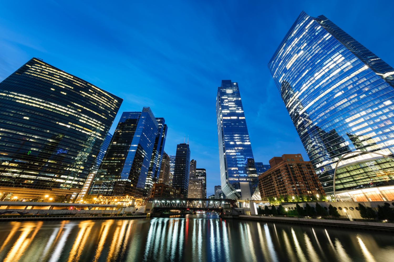 Wide lens view of skyscraper offices over a river with lights reflecting in the water